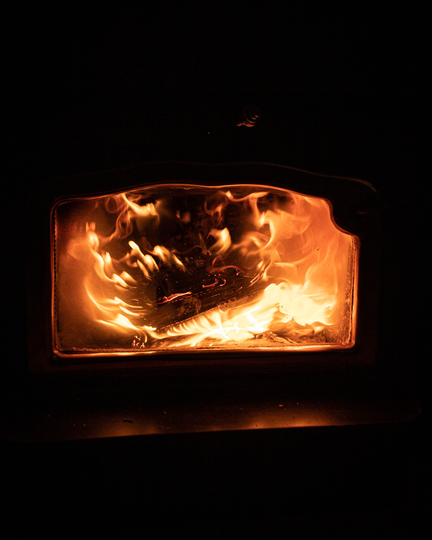 A head-on shot shows a roaring fire inside of a woodstove. 