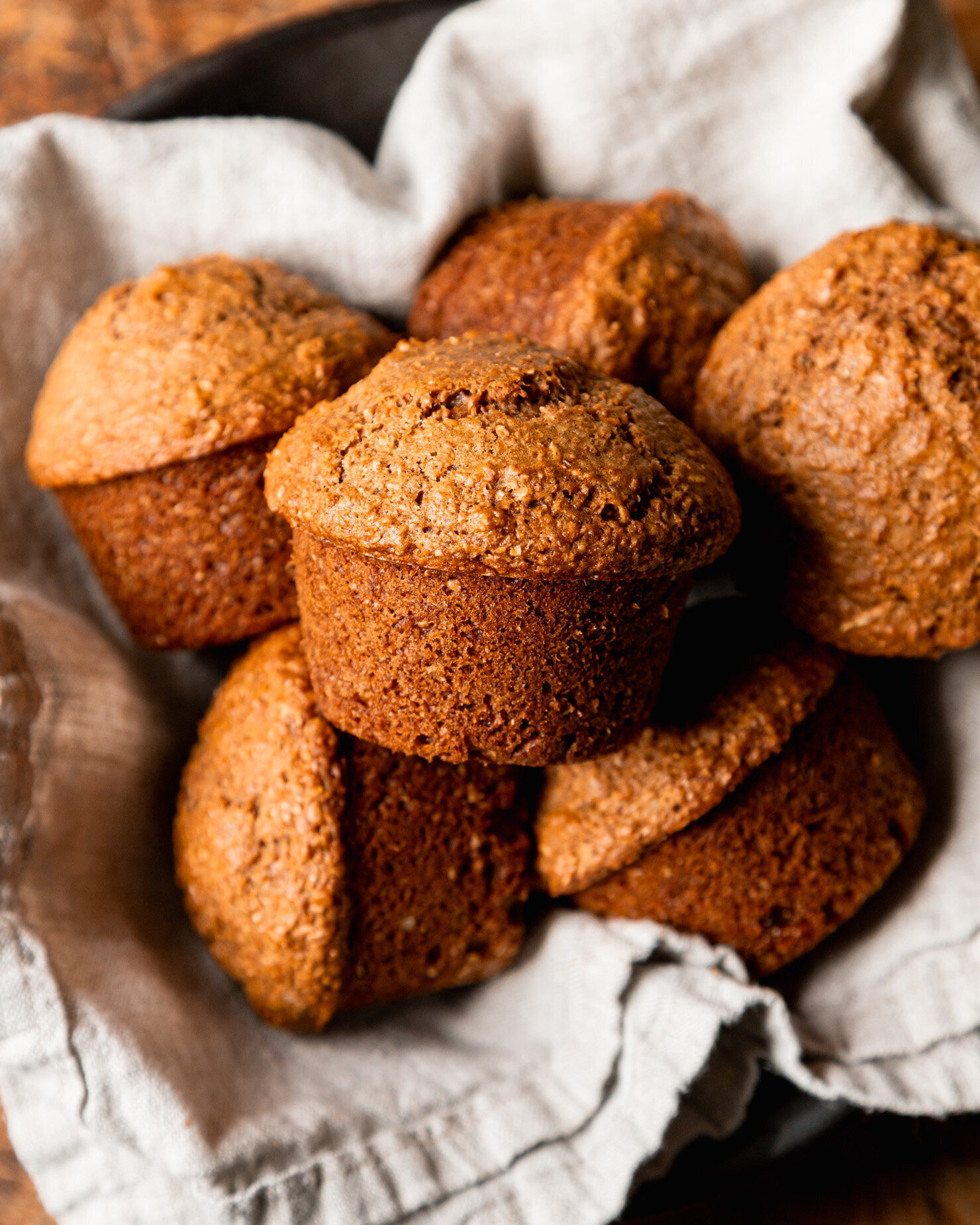 An overhead shot shows vegan bran muffins nestled into a linen-lined bowl.